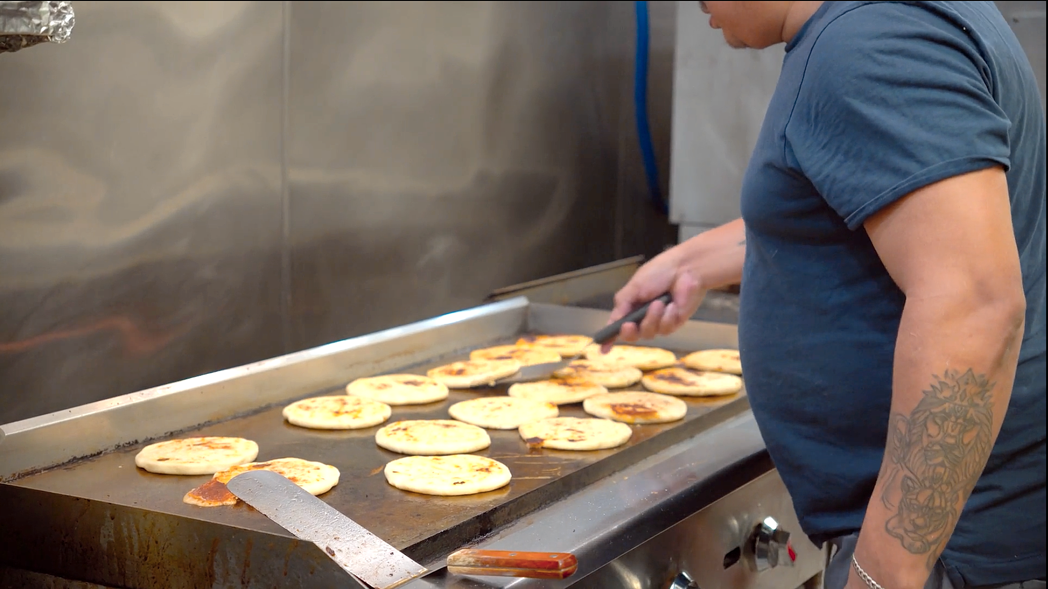 Handmade pupusas cooking on the griddle